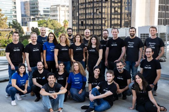 Swimm team employee photo on rooftop in city scape.