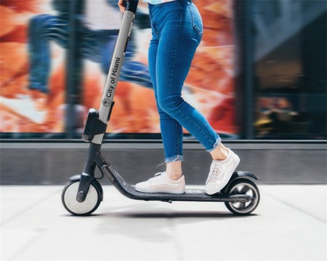 woman riding e-scooter that says city of miami