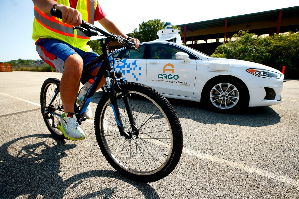 cyclist riding next to argo ai autonomous vehicle