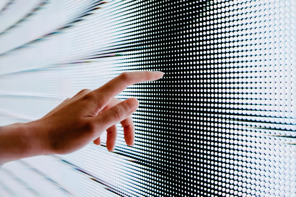 Closeup of woman's hand touching illuminated LED display screen to represent solving small data problems.