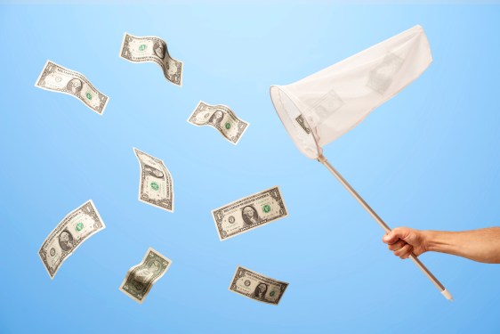 Man's hand with butterfly net catching US 1 dollar bills that are floating in mid air on blue background