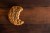 An oatmeal chocolate chip cookie with a bite out of it on a walnut wood board.