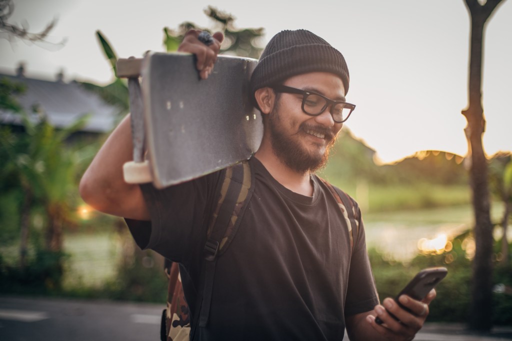 Skater using smartphone on the street, used in a profile of fintech startup Brankas