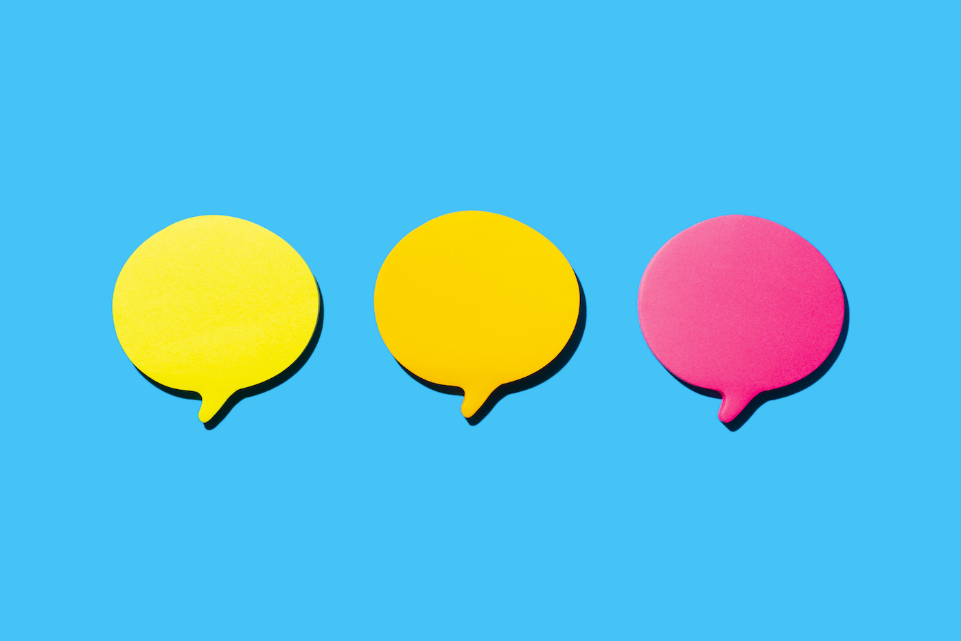 Yellow, Orange And Fuchsia Blank Notes In The Shape Of Comic Bubbles. Blue Background.