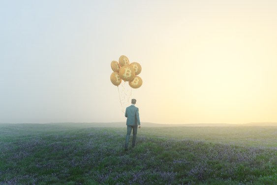 Image of a businessman walking with bitcoin balloons.