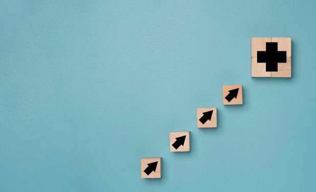 Plus sign and increasing arrow print screen on wooden cube block on blue background which it mean positive sign such as more benefit thinking and mindset concept. (Plus sign and increasing arrow print screen on wooden cube block on blue background whi
