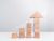 Wooden blocks stacking as an arrow up averages as a growth graph chart on white background.