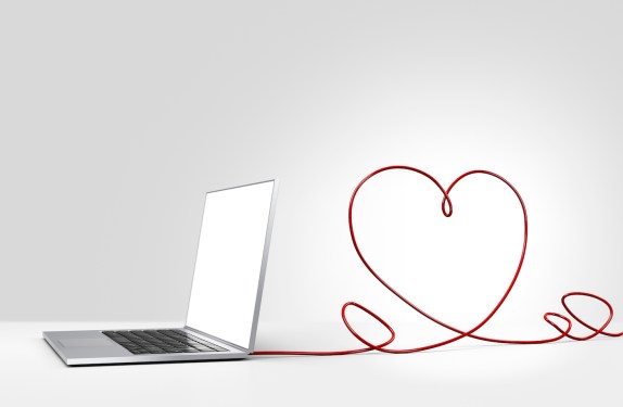 Laptop computer with ethernet cable forming a heart, coming out of the back on a plain background