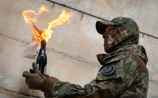 A local resident prepares to use a Molotov cocktail against a wall during an all-Ukrainian training campaign "Don't panic! Get ready!" close to Kyiv, Ukraine, Sunday, Feb. 6, 2022