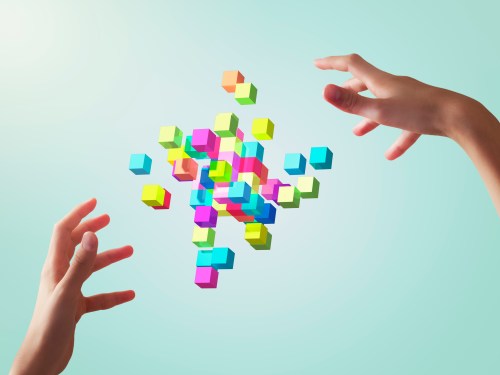 Image of colorful cubes forming geometric shapes between girl's hands.