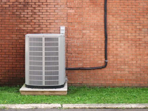 Image of an air-conditioning unit against a brick wall.