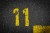 sign on the asphalt, yellow painted number eleven on grey street, yellow lines like a corner on the road, space for text