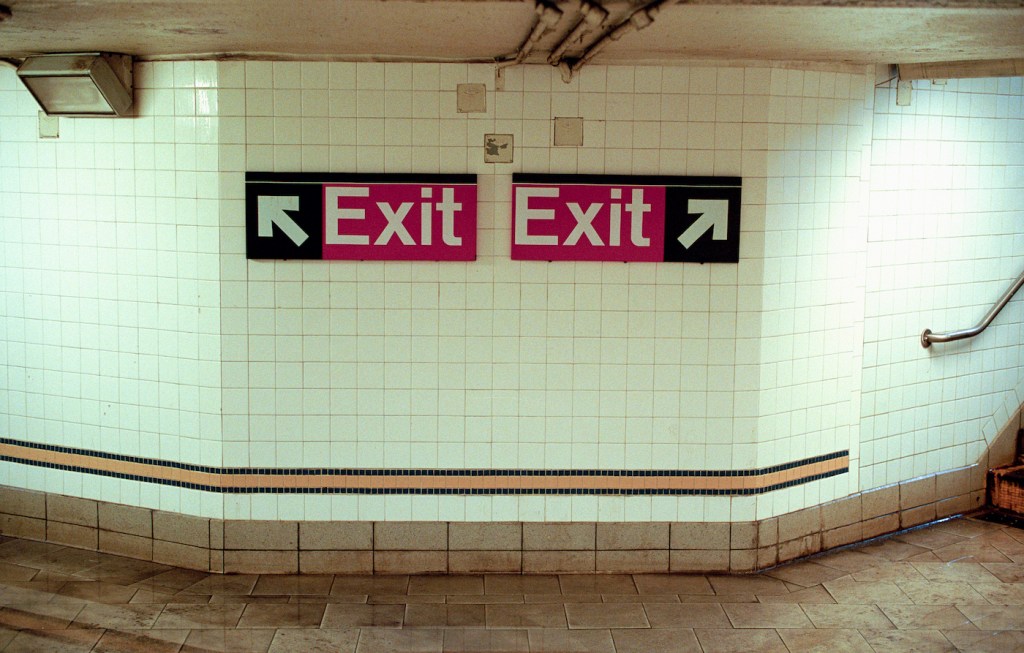 Two Subway Exit Signs Pointing in Opposite Directions