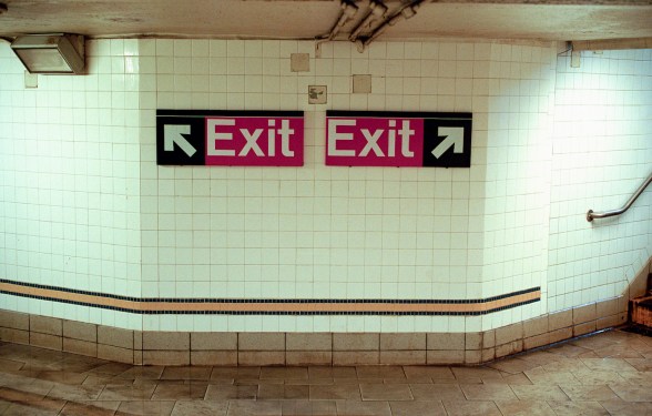 Two Subway Exit Signs Pointing in Opposite Directions