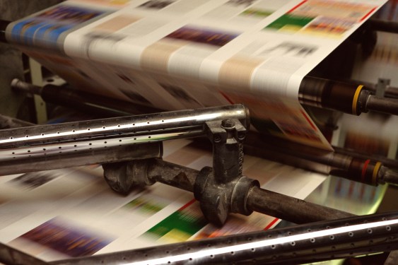 Image of paper moving through a printing press.