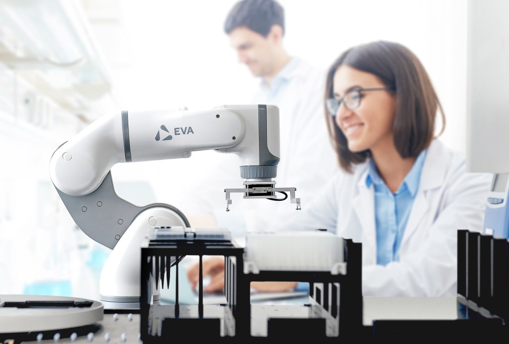 A robotic arm interacts with vials in a lab setting.