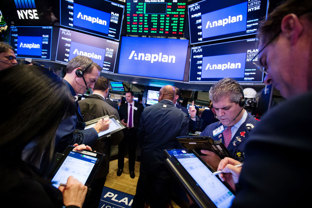 Traders work beneath monitors displaying Anaplan Inc. signage during the company's initial public offering (IPO) on the floor of the New York Stock Exchange (NYSE) in New York, U.S., on Friday, Oct. 12, 2018. U.S. stocks surged Friday after two days of market tumult as trade tensions with China seemed to ease, at least temporarily, with the countries planning to meet in November and the Treasury Department saying that China isn't manipulating its currency. Photographer: Michael Nagle/Bloomberg via Getty Images