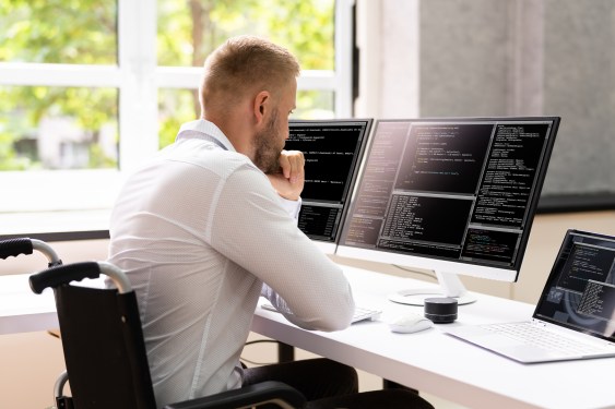 Computer Programmer Writing Program Code On Computer In Office