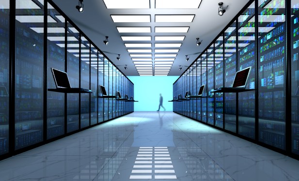 Empty data center with person walking away at the far end.