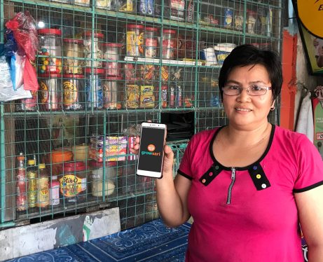 A store owner in the Philippines with a smartphone displaying GrowSari's app