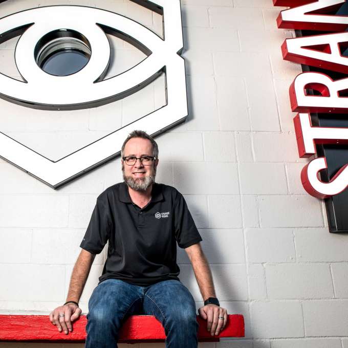 Austin-based serial entrepreneur Will Hurley sitting on a bench in front of a wall at Strangeworks