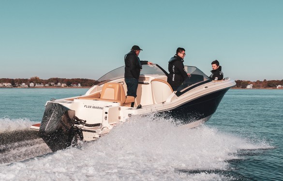 3 people in a speedboat with an electric motor on the water.