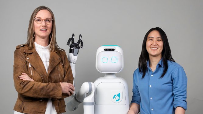 Diligent Robotics co-founders, Dr. Andrea Thomaz and Dr. Vivian Chu pose with Moxi, a robot they created to help take the stress off of nurses and clinical care teams.