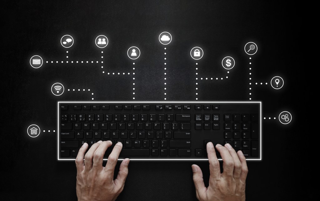 Hands typing on computer keyboard with application programming interface icons.