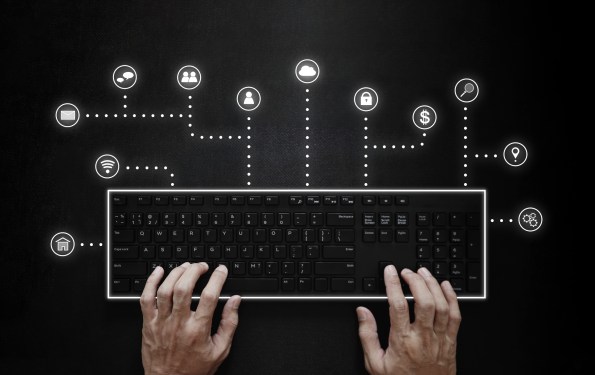 Hands typing on computer keyboard with application programming interface icons.