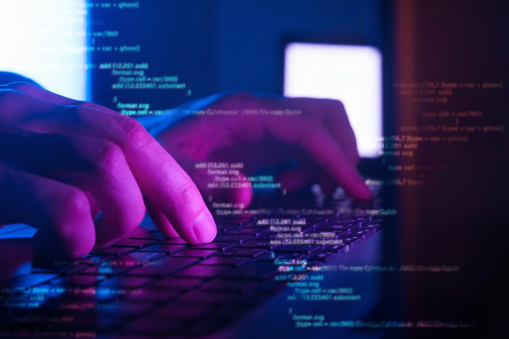 Coder's hands on keyboard over code.