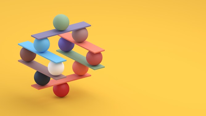 Image of multicolored balls and planks stacked carefully on a yellow background.