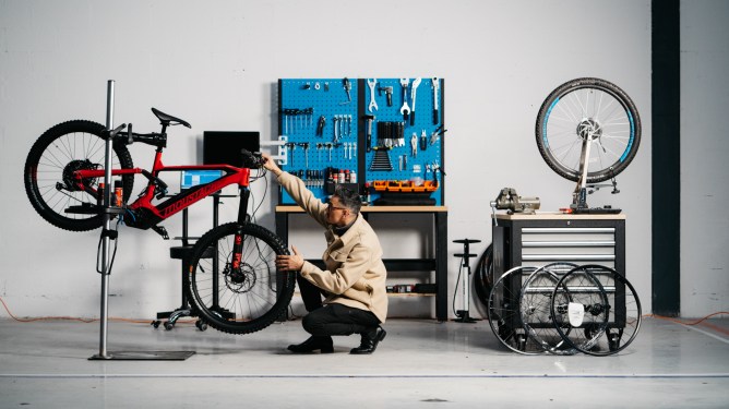 A bike repair person checking the front wheel of a bike