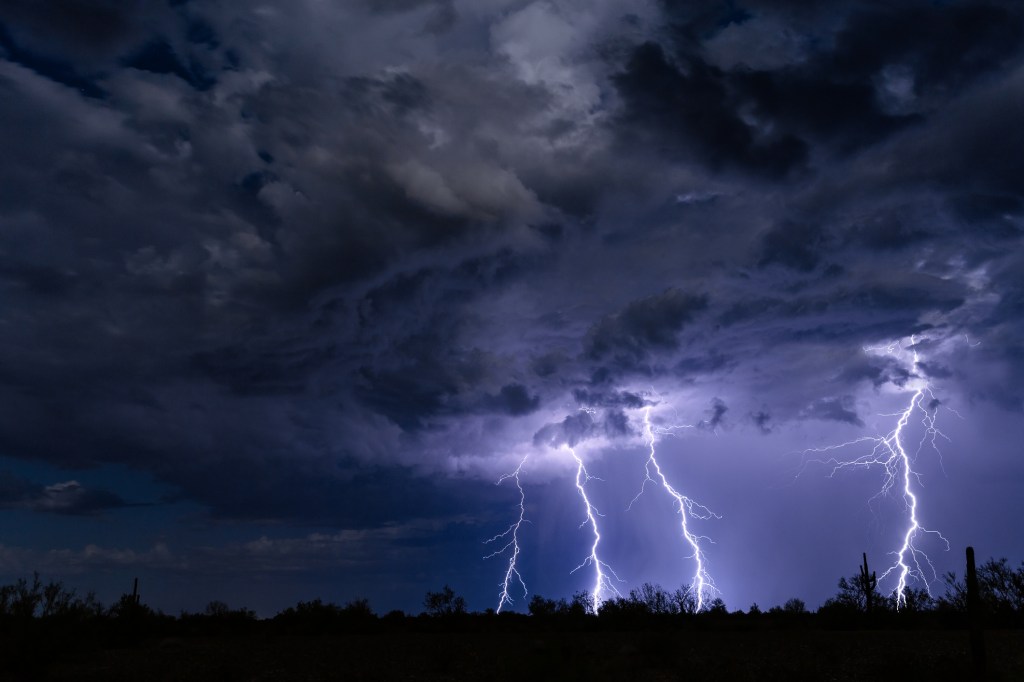 Low Angle View Of Lightning Over Silhouette Landscape At Night