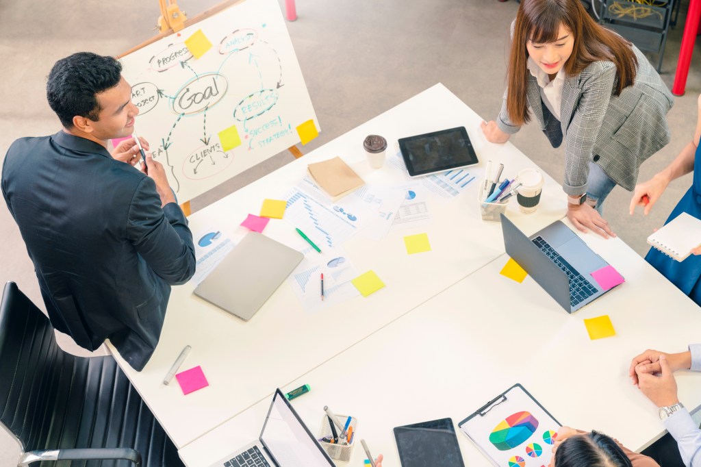 Group of workers brainstorming project on a whiteboard.