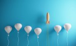 Orange colored rocket rising on the top between the hot air balloons. ( 3d render )