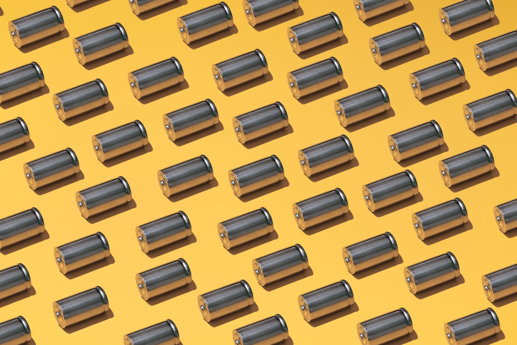 A large group of batteries laid in a pattern on a yellow background