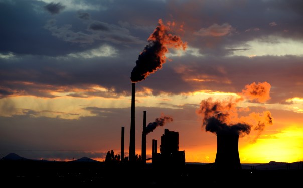 Coal power station with smoking chimneys in sunset with cloudy sky, industrial landscape