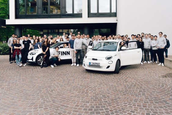 Finn's employees pose around white electric Fiat 500
