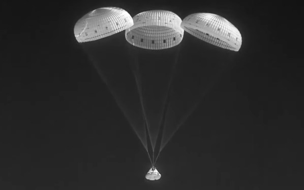 Starliner floating under three parachutes.