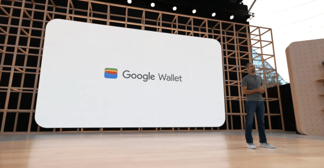 Man onstage in front of large screen displaying Google Wallet logo