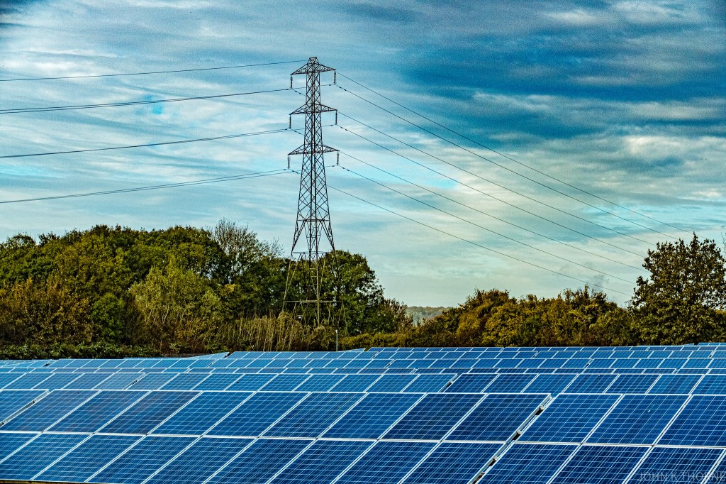 A solar farm beneath a pylon
