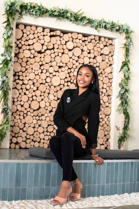 A black woman in a suit smiles to the camera