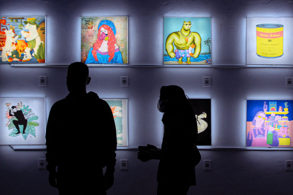 Visitors observe Non-Fungible Token (NFT) works at an exhibition entitled Indo NFT Festiverse at the RJ Katamsi Gallery, Indonesian Art University which combines art and technology in Yogyakarta on April 13, 2022. - RESTRICTED TO EDITORIAL USE - MANDATORY MENTION OF THE ARTIST UPON PUBLICATION - TO ILLUSTRATE THE EVENT AS SPECIFIED IN THE CAPTION (Photo by DEVI RAHMAN / AFP) / RESTRICTED TO EDITORIAL USE - MANDATORY MENTION OF THE ARTIST UPON PUBLICATION - TO ILLUSTRATE THE EVENT AS SPECIFIED IN THE CAPTION / RESTRICTED TO EDITORIAL USE - MANDATORY MENTION OF THE ARTIST UPON PUBLICATION - TO ILLUSTRATE THE EVENT AS SPECIFIED IN THE CAPTION (Photo by DEVI RAHMAN/AFP via Getty Images)