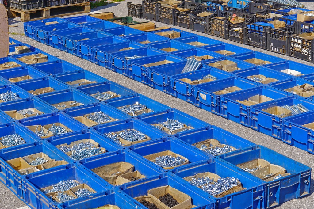 Nuts and bolts in crates on a manufacturing floor.