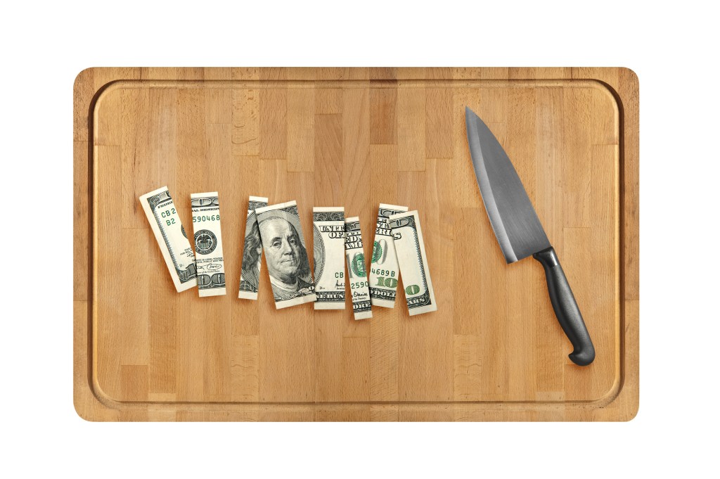 Knife and sliced hundred dollar on Wooden cutting board. isolated on white background.