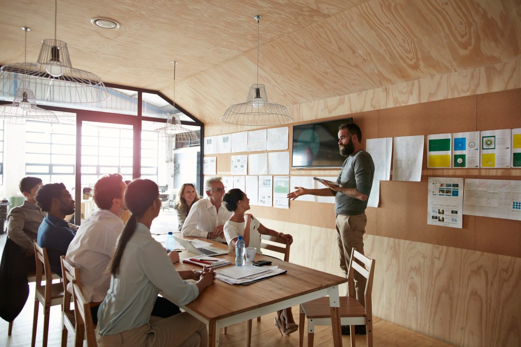 Team working on an application design plan in a conference room with lots of examples hanging from the walls.