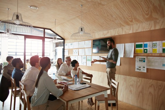 Team working on an application design plan in a conference room with lots of examples hanging from the walls.
