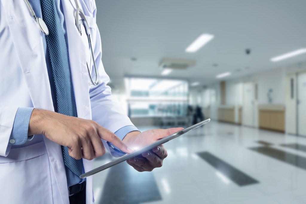 Close-up of a physician's hands holding a tablet, used in a post about healthcare startup Regard