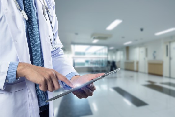 Close-up of a physician's hands holding a tablet, used in a post about healthcare startup Regard