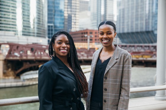 Two women stand side by side, smiling at the camera